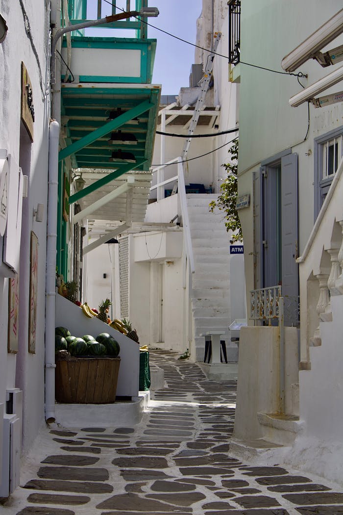 Explore a picturesque alley in Mykonos featuring iconic whitewashed buildings and vibrant accents.